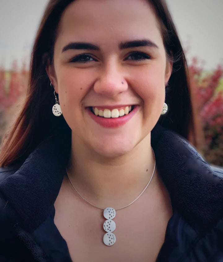 Smiling woman in black jacket with silver jewelry outdoors