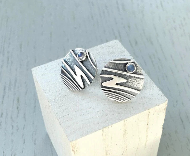 Textured round earrings with wavy patterns and small blue stones on top