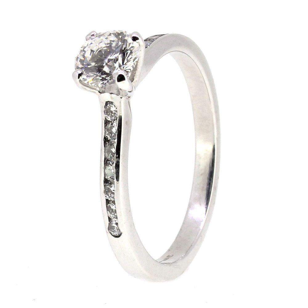 Silver engagement ring with round diamond and side stones on a white background